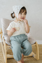 Toddler Girl Sitting in Avauma Le Petite White Oat Short Sleeve T-Shirt, Matched with Loose-Fit Pants